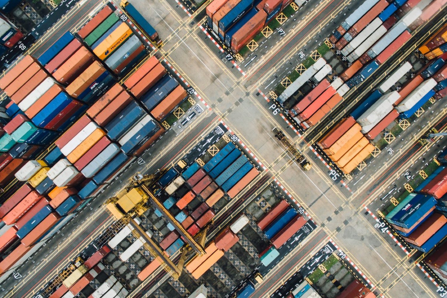 Overhead view of a container terminal with colour-coded shipping containers and marked lanes